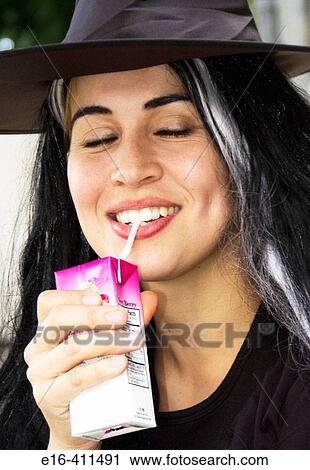 Stock Image - Woman drinking juice in witch costume. Fotosearch