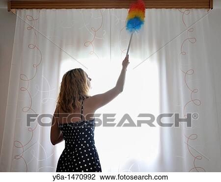 Stock Image - Woman dusting curtains. Fotosearch