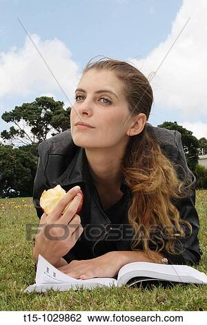 woman eating an apple in a park while reading a book View Large Photo Image Stock Image - woman eating an apple in a park while reading a book. Fotosearch