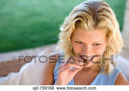 Woman eating chocolate View Large Photo Image Stock Photo - Woman eating chocolate. Fotosearch