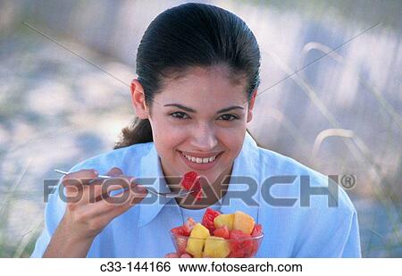 Woman eating fruit salad View Large Photo Image Stock Photograph - Woman eating fruit salad. Fotosearch