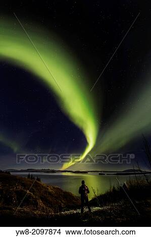 Woman enjoying the view of the Northern Lights, at Lake Thingvellir, Iceland. Thingvellir National Park is a UNESCO World Heritage Site. View Large Photo Image Picture - Woman enjoying the view of the Northern Lights, at Lake Thingvellir, Iceland. Thingvellir National Park is a UNESCO World Heritage Site.. Fotosearch