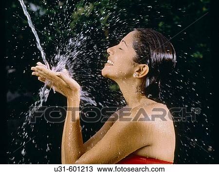 Woman enjoys a splash of water in the garden View Large Photo Image Stock Image - Woman enjoys a splash of water in the garden. Fotosearch