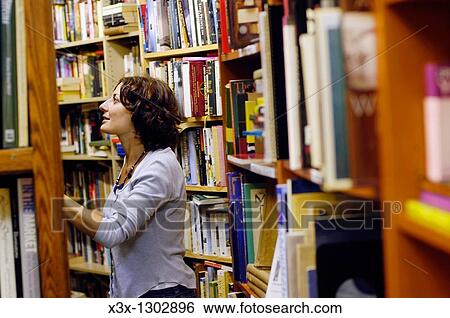 Stock Photograph - Woman enthusiastically admiring books in a book store. Fotosearch