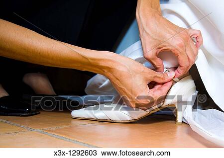 Woman fastening bride shoes View Large Photo Image Stock Image - Woman fastening bride shoes. Fotosearch