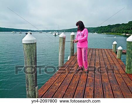 Stock Image - Woman fishing from a private dock on Lagoon Pond at Martha's Vineyard, Massachusetts.. Fotosearch