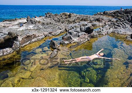 Woman floating in colorful water pool by the sea Pantelleria Island, Sicily, Italy View Large Photo Image Picture - Woman floating in colorful water pool by the sea Pantelleria Island, Sicily, Italy. Fotosearch