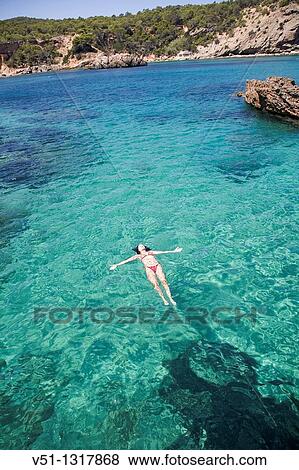 Woman floating in water at a beach in Portinatx, Ibiza, Balearic Islands, Spain View Large Photo Image Stock Photo - Woman floating in water at a beach in Portinatx, Ibiza, Balearic Islands, Spain. Fotosearch