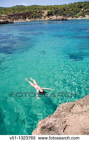 Woman floating in water at a beach in Portinatx, Ibiza, Balearic Islands, Spain View Large Photo Image Stock Photography - Woman floating in water at a beach in Portinatx, Ibiza, Balearic Islands, Spain. Fotosearch