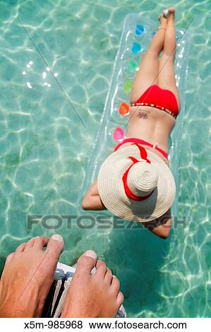 Woman floating on lilo in tropical lagoon with man above watching View Large Photo Image Stock Photo - Woman floating on lilo in tropical lagoon with man above watching. Fotosearch