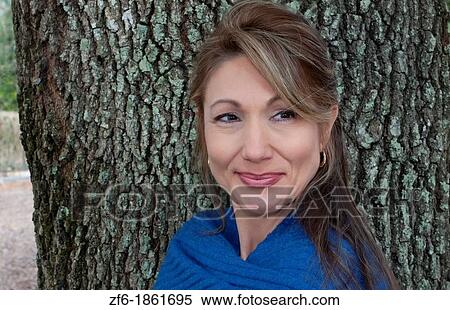 Woman from Eastern Europe portrait against tree in park with blue shawl smiling View Large Photo Image Stock Photography - Woman from Eastern Europe portrait against tree in park with blue shawl smiling. Fotosearch