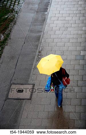 Woman goes with yellow umbrella View Large Photo Image Stock Photo - Woman goes with yellow umbrella. Fotosearch