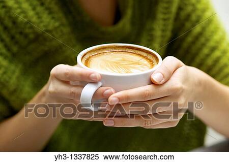 Woman hand holding a cup of cappuccino close up View Large Photo Image Stock Photography - Woman hand holding a cup of cappuccino close up. Fotosearch