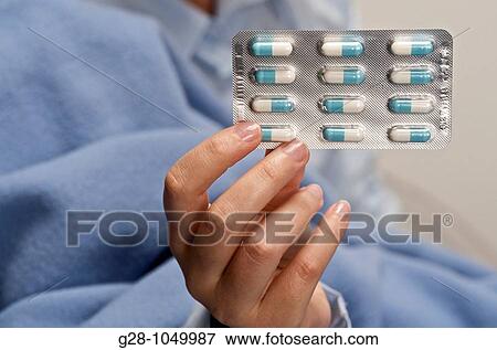 woman hand in pyjamas holding a pack of pills from under a blue blanket View Large Photo Image Stock Photo - woman hand in pyjamas holding a pack of pills from under a blue blanket. Fotosearch