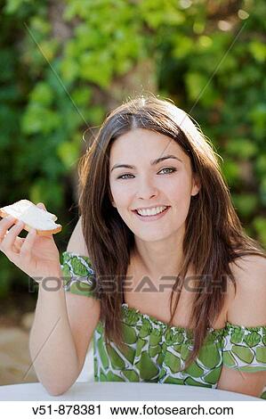 Stock Image - Woman having a breakfast outdoor. Fotosearch