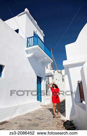 Stock Image - Woman having a walk in town center, Amorgos, Cyclades Islands, Greek Islands, Greece, Europe.. Fotosearch