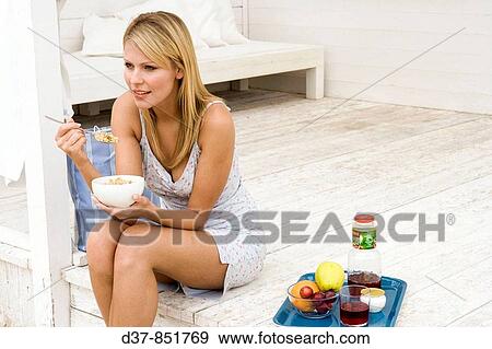 Stock Photo - Woman having breackfast in the terrace. Fotosearch