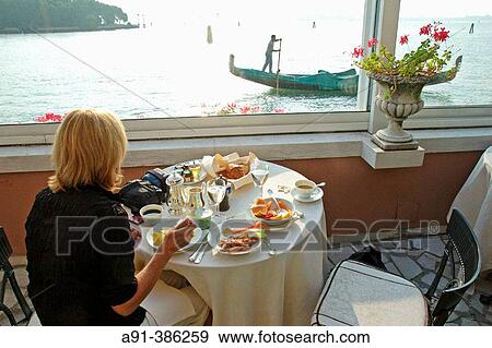 Woman having breakfast on the Hotel Cipriani Terrace, gondola passing by at back. Giudecca island. Venice. Venetia. Italy View Large Photo Image Stock Photo - Woman having breakfast on the Hotel Cipriani Terrace, gondola passing by at back. Giudecca island. Venice. Venetia. Italy. Fotosearch