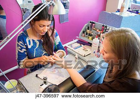 Woman having her nail done with a nail therapist in a salon View Large Photo Image Stock Photo - Woman having her nail done with a nail therapist in a salon. Fotosearch