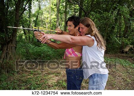 Woman Helping Friend Shoot Arrow With Slingshot View Large Photo Image Picture - Woman Helping Friend Shoot Arrow With Slingshot. Fotosearch
