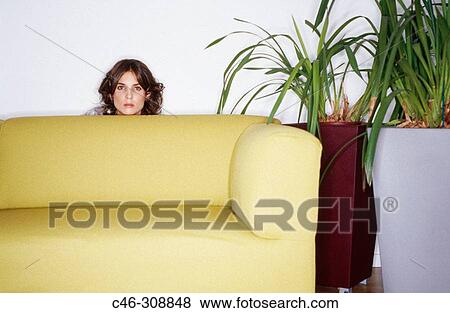 Stock Photo - Woman hiding behind couch. Fotosearch