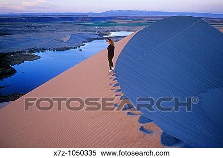 Woman hiking the sand dunes during sunset at Bruneau Dunes State Park near the town of Bruneau in southern Idaho USA View Large Photo Image Stock Photography - Woman hiking the sand dunes during sunset at Bruneau Dunes State Park near the town of Bruneau in southern Idaho USA. Fotosearch