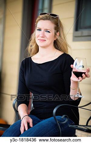 Woman holding a glass of red wine while sitting in front of her house View Large Photo Image Stock Photograph - Woman holding a glass of red wine while sitting in front of her house. Fotosearch
