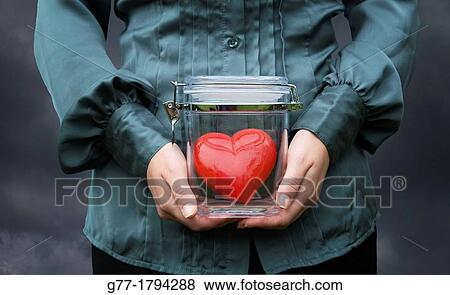 Stock Photo - Woman holding a jar with a heart. Fotosearch