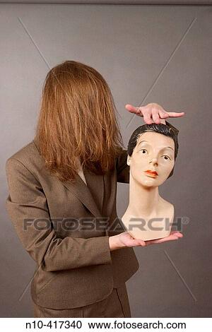 Woman, holding a mannequin head, while her long hair completely covers her face. View Large Photo Image Stock Image - Woman, holding a mannequin head, while her long hair completely covers her face.. Fotosearch