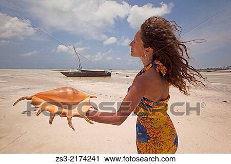 Woman holding a sea shell, Jambiani, Zanzibar Island, Tanzania, Indian Ocean, East Africa. View Large Photo Image Stock Image - Woman holding a sea shell, Jambiani, Zanzibar Island, Tanzania, Indian Ocean, East Africa.. Fotosearch