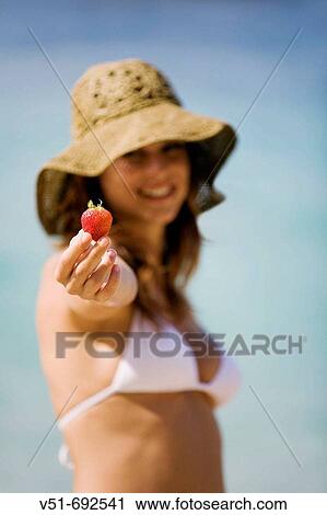 Woman holding a strawberry on the beach View Large Photo Image Stock Image - Woman holding a strawberry on the beach. Fotosearch