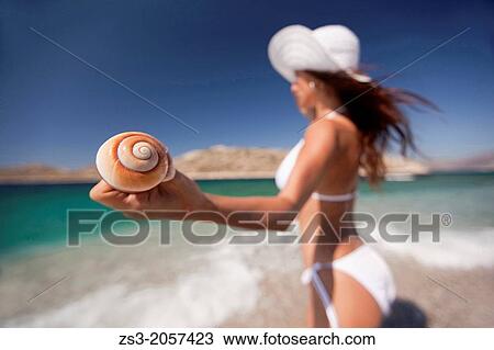 Stock Image - Woman holding a winkle in her hand, Naxos, Cyclades Islands, Greek Islands, Greece, Europe.. Fotosearch