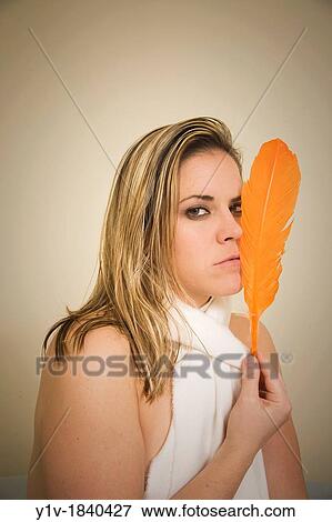 Woman holding an orange feather View Large Photo Image Stock Photo - Woman holding an orange feather. Fotosearch