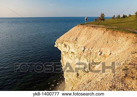Stock Photo - Woman Holding Baby and Standing on Steep Panga Cliff by Sea in Saare County, Estonia. Fotosearch