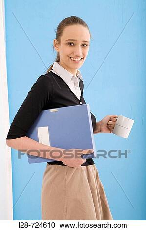 Woman holding cup and document folder, smiling View Large Photo Image Stock Image - Woman holding cup and document folder, smiling. Fotosearch