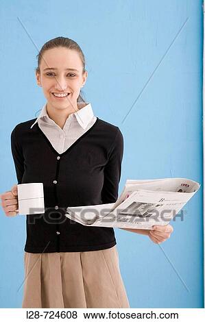 Woman holding cup and newspaper, smiling View Large Photo Image Stock Photo - Woman holding cup and newspaper, smiling. Fotosearch