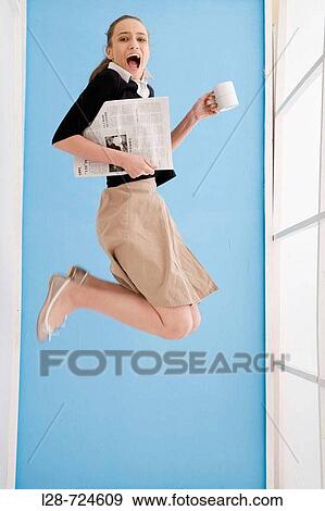 Woman holding cup and newspaper, smiling, jumping View Large Photo Image Stock Photo - Woman holding cup and newspaper, smiling, jumping. Fotosearch