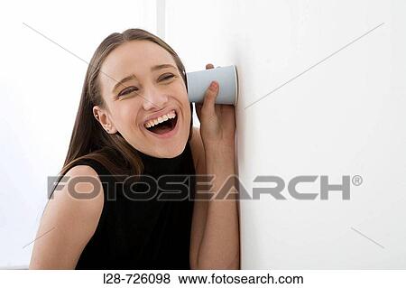 woman holding Disposable Cup against wall, listening View Large Photo Image Stock Photo - woman holding Disposable Cup against wall, listening. Fotosearch