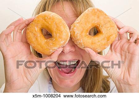 Woman holding donuts up in front of her eyes View Large Photo Image Picture - Woman holding donuts up in front of her eyes. Fotosearch