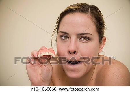 Woman holding false teeth View Large Photo Image Stock Photograph - Woman holding false teeth. Fotosearch