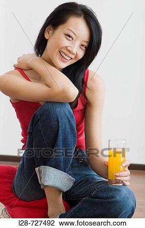 Stock Image - Woman holding glass orange juice. Fotosearch