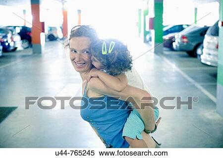 Woman holding her daughter in a car parking View Large Photo Image Stock Photography - Woman holding her daughter in a car parking. Fotosearch