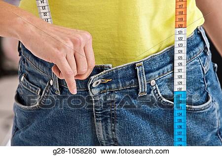 woman holding her too tight or too large jeans, dieting, with a measuring tape hanging from her neckclose up View Large Photo Image Stock Image - woman holding her too tight or too large jeans, dieting, with a measuring tape hanging from her neckclose up. Fotosearch