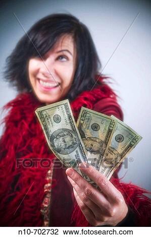 Stock Image - Woman holding three American twenty dollar bills.. Fotosearch
