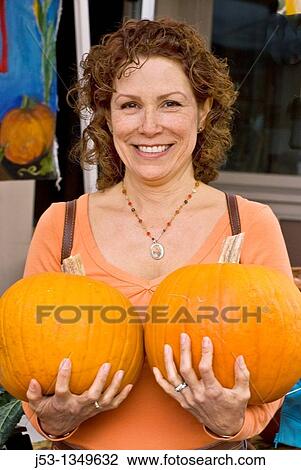 Woman holding two pumpkins at farmers? market, Nevada City, California View Large Photo Image Stock Image - Woman holding two pumpkins at farmers? market, Nevada City, California. Fotosearch