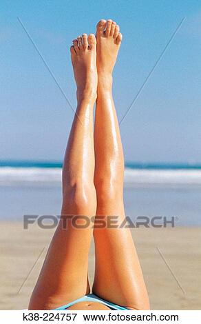 Stock Photo - Woman in a beach with her legs up. Fotosearch