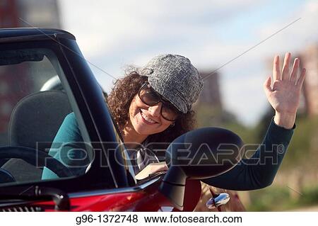 Stock Photo - woman in a convertible relaxing at the beach. Fotosearch