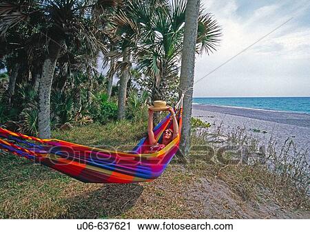 Woman in a hammock in Florida at the beach holding up a straw hat and looking View Large Photo Image Stock Image - Woman in a hammock in Florida at the beach holding up a straw hat and looking. Fotosearch