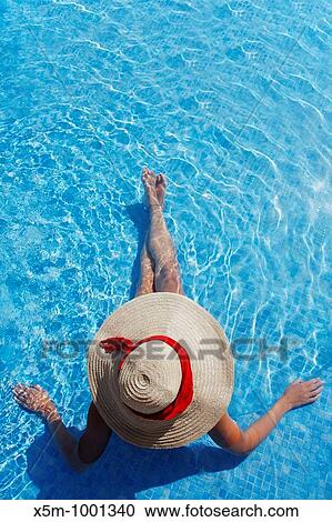 Woman in a sun hat sunbathing in a blue swimming pool View Large Photo Image Stock Image - Woman in a sun hat sunbathing in a blue swimming pool. Fotosearch
