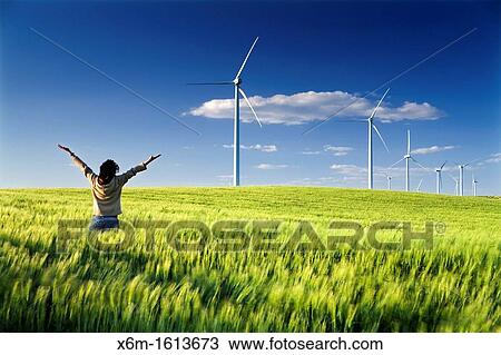Stock Image - woman in a windmills field, windfarm. Fotosearch